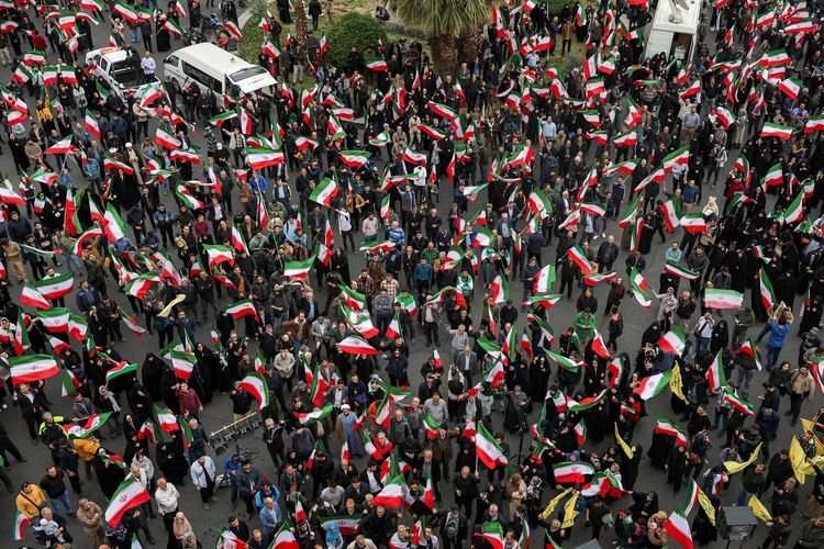 Pengunjuk rasa di Teheran mengibarkan bendera untuk mendukung Pemerintah Iran dan memprotes serangan gabungan Amerika Serikat-Israel, di luar salah satu masjid di Teheran, Sabtu (28/2/2026). Serangan tersebut berujung tewasnya Pemimpin Tertinggi Ayatollah Ali Khamenei.(AFP/ATTA KENARE)