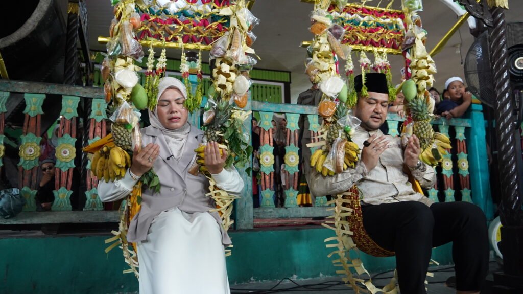 Wakil Wali Kota Banjarmasin Hj. Ananda mengikuti prosesi Baayun Maulid dengan mengenakan ayunan yang dihiasi berbagai hasil bumi dan perlengkapan tradisional. Foto Dok Istimewa