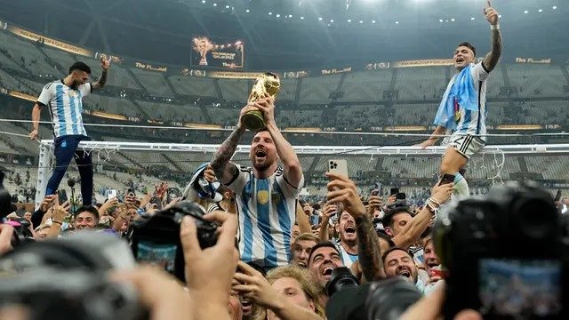 Pemain Argentina Lionel Messi mengangkat trofi juara di depan para penggemar usai mengalahkan Prancis pada pertandingan sepak bola final Piala Dunia 2022 di Stadion Lusail, Lusail, Qatar, 18 Desember 2022. Argentina menang 4-2 dalam adu penalti setelah pertandingan berakhir imbang 3 -3. (AP Photo/Martin Meissner)